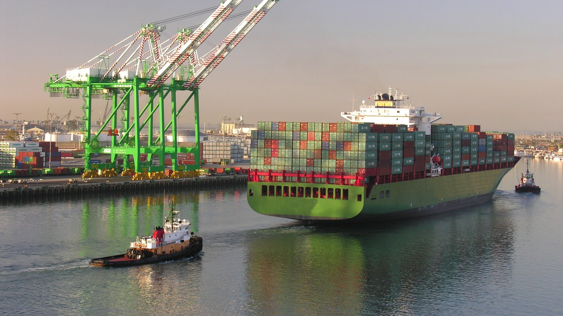 Containerschiff beim be- und entladen in einem Hafen mit mehreren Kränen