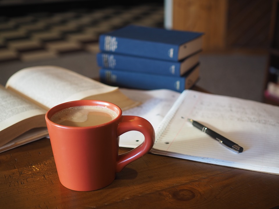 Eine Kaffeetasse und Schreibutensilien liegen auf einem Tisch