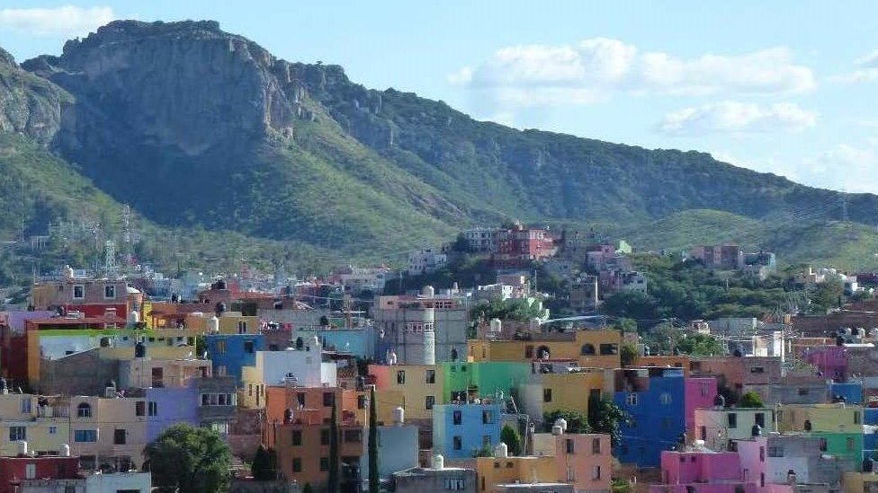 Viele bunte Häuser mit einer Berglandschaft im Hintergrund