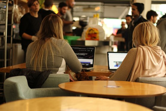 Zwei Studentinnen sitzen zusammen an ihrem Laptop