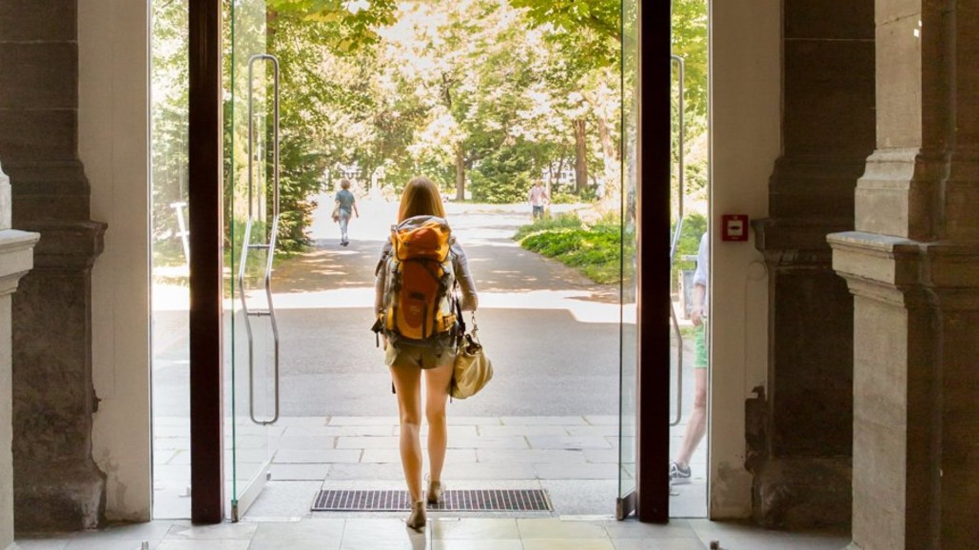 Eine Studentin läuft aus dem HfT-Gebäude am Hauptausgang heraus