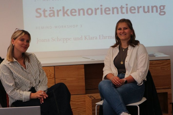 Zwei Kursleiterinnen sitzen vor einer Präsentation mit dem Titlel Stärkenorientierung