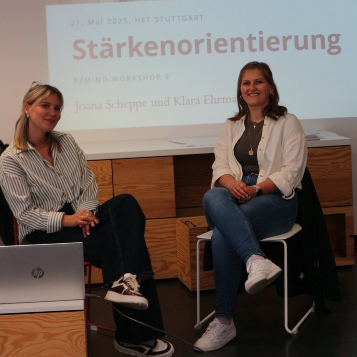 Zwei Kursleiterinnen sitzen vor einer Präsentation mit dem Titlel Stärkenorientierung