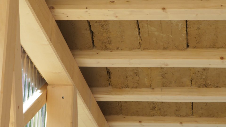 zu sehen ist das Rauminnere mit Stützen und Trägern aus Holz sowie einer gewölbten Decke aus Lehmziegeln