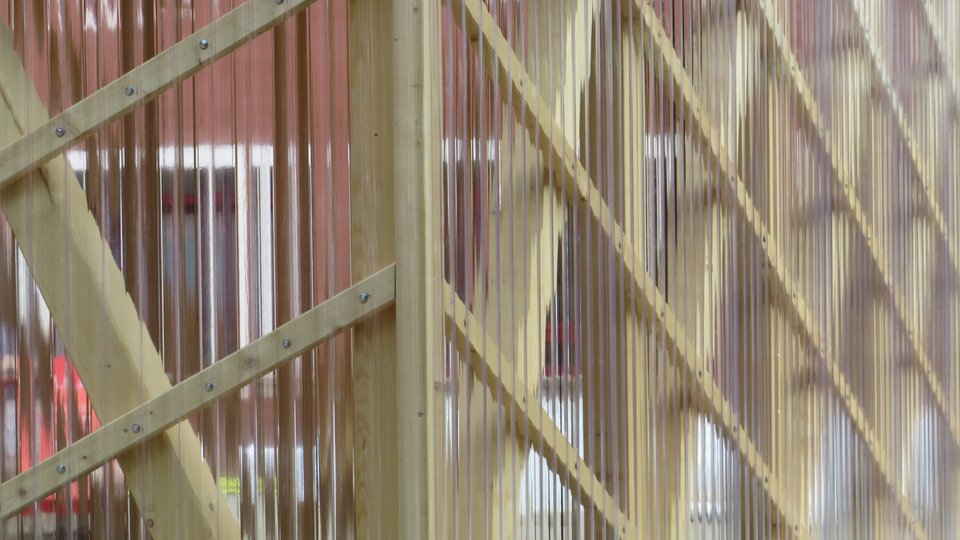 Außenansicht eines Pavillons mit Stützen und Diagonalstreben aus Holz sowie durchsichter Plexiglas-Fassade