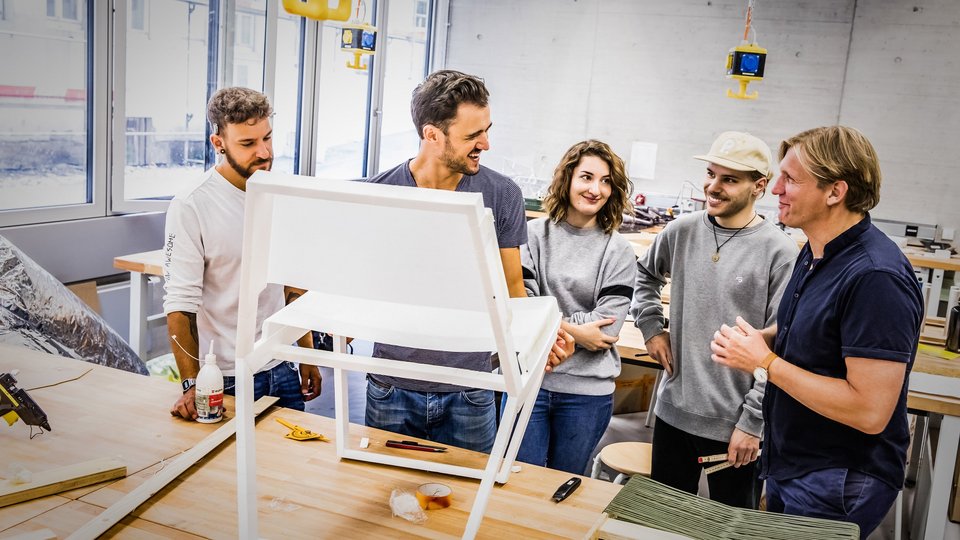 Studierende mit Professor im Gespräch in Werkstatt 