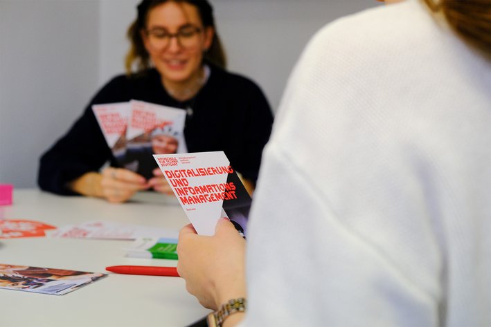 Zwei Studierende betrachten Studiengangsflyer