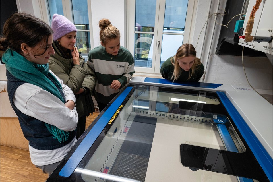 Fotografie des Labors für Digitale Fertigung, Studierende beobachten Lasercutter