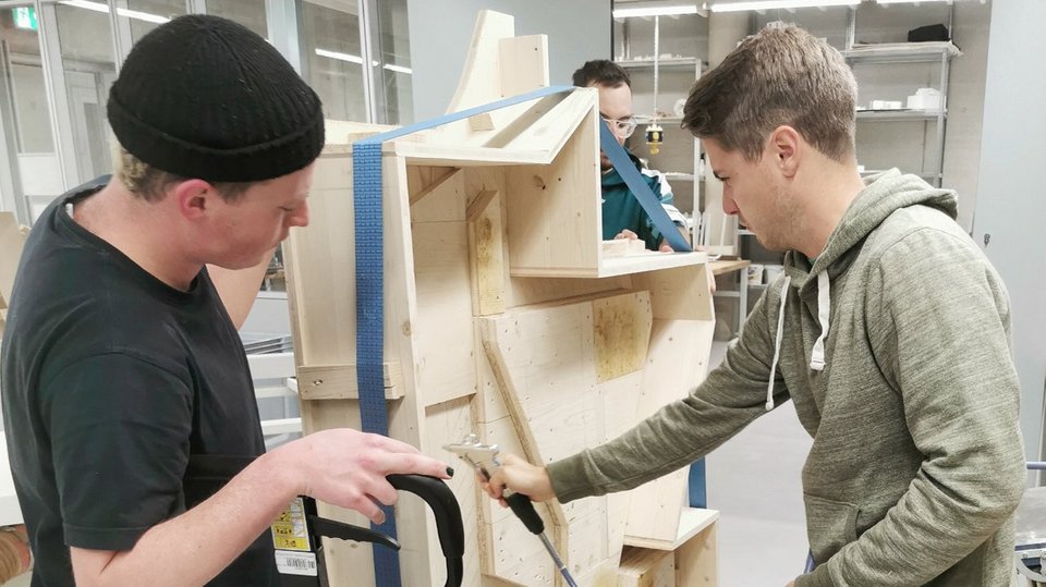 Studierende bei der Bearbeitung einer Holzschalung für ein Stampflehmmodell