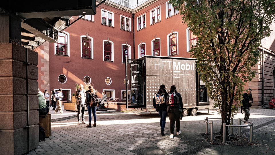 Studierende im Innenhof zwichen Bau 1 und Bau 2 mit HFT Mobil