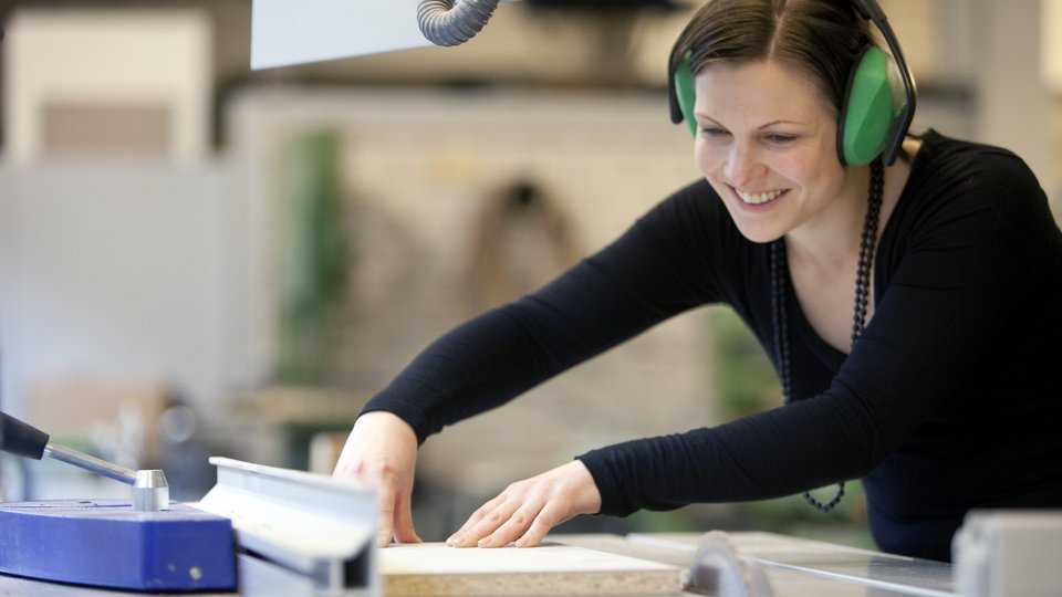 Eine Studentin arbeitet mit Holz in der Modellbauwerkstatt