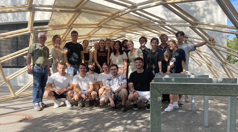 Gruppenbild mit Studierendem mit Pavillionstruktur aus Holz im Hintergrund