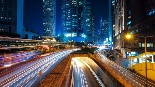 Eine stark befahrene Straße in Hongkong und Hochhäuser bei Nacht