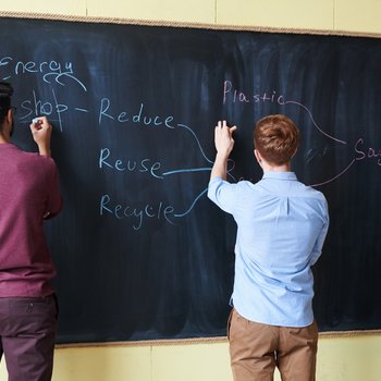 Drei Studierende schreiben an eine Tafel