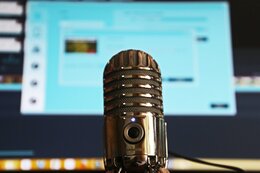 Podcast-Mikrophon vor einem Monitor 
