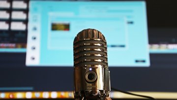 Podcast-Mikrophon vor einem Monitor 