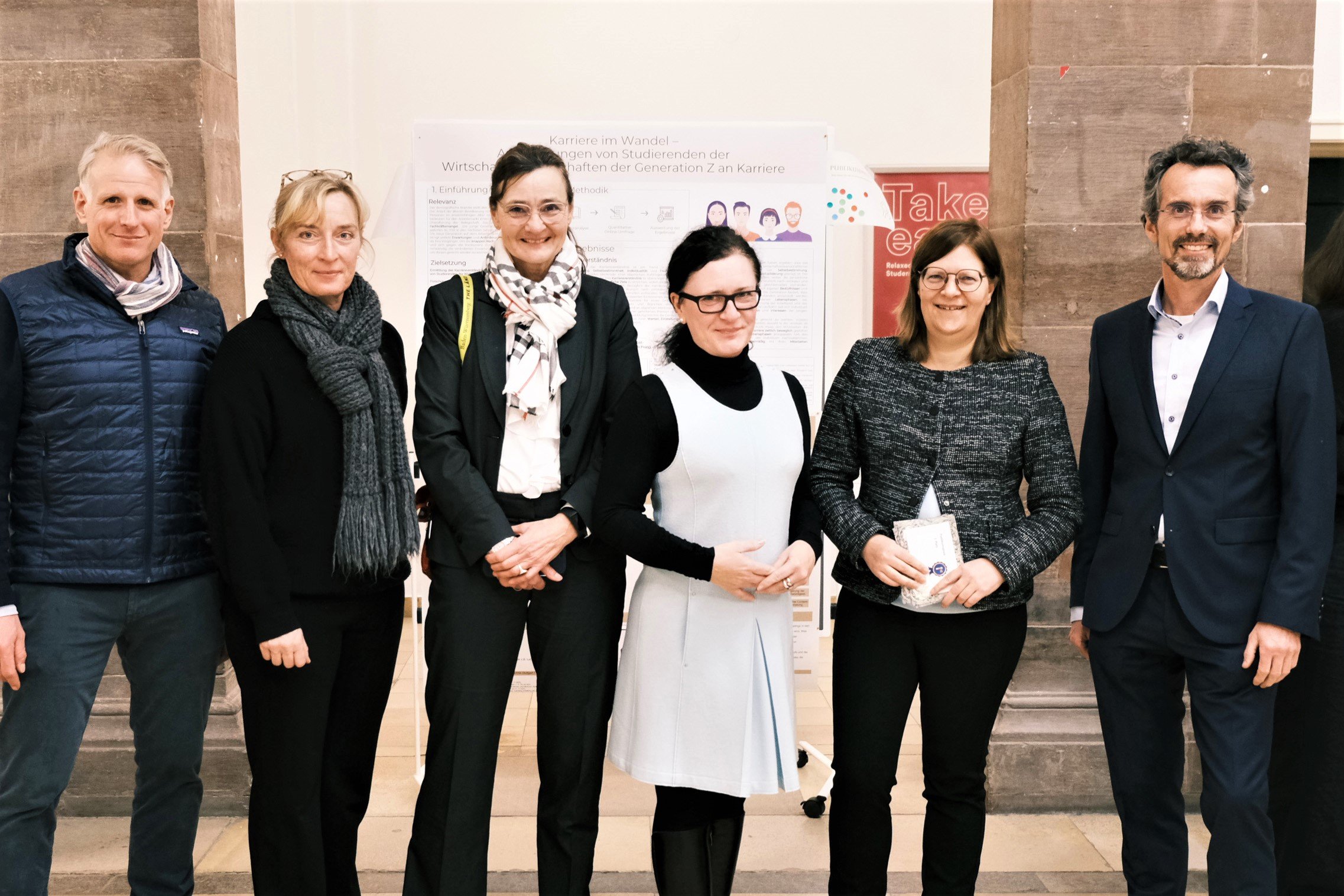 6 Personen stehen vor einem Plakat