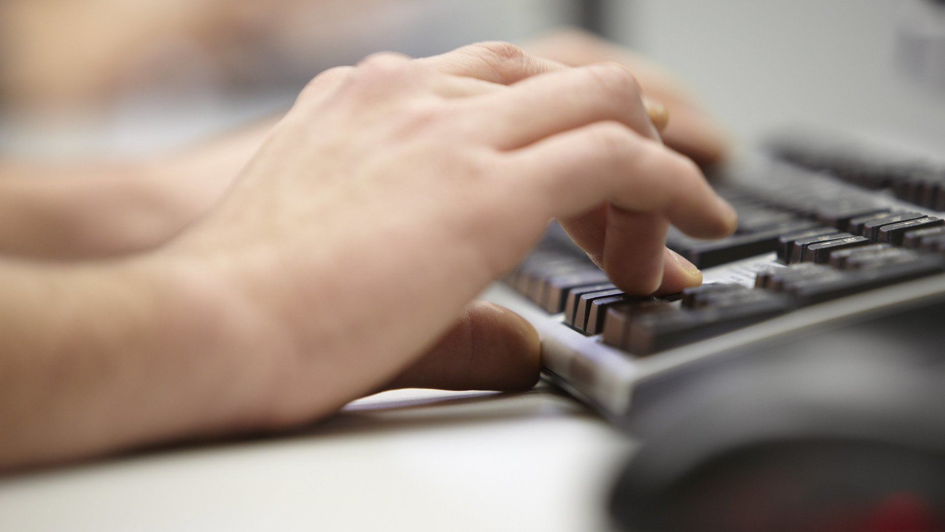 Eine Hand schreibt auf einer Tastatur