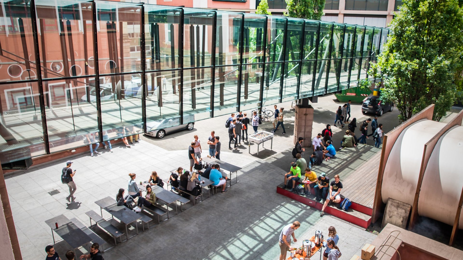 Studierende sitzen im Innenhof bei Sonnenschein zusammen