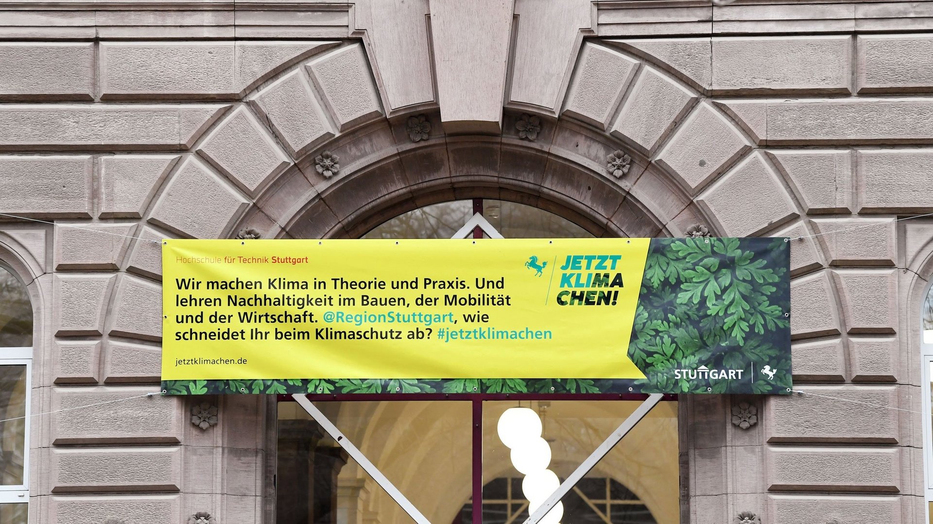 Banner zur Klimaschutzkampagne am Eingang von Bau 1