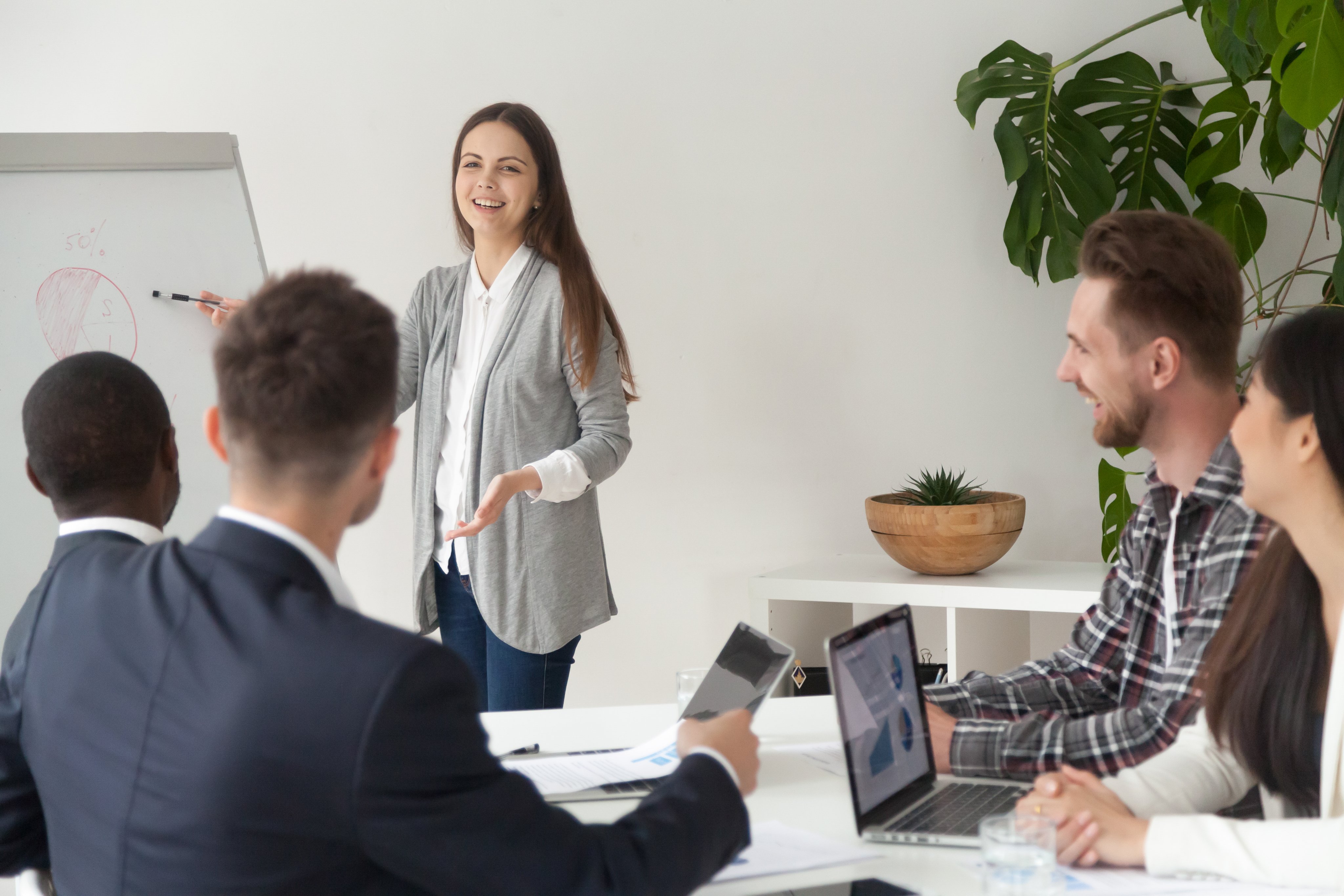 Smiling young employee giving presentation working with flipchart