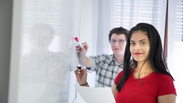 Studentin schreibt etwas an einer Metaplanwand