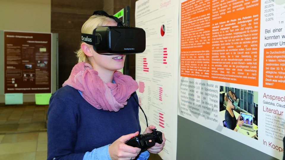 Auf dem Bild ist eine Studentin beim Austesten einer VR-Brille zu sehen.