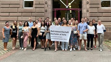 Die Absolvent:Innen der Betriebswirtschaft (Bachelor) an der HFT stehen in einer Gruppe zusammen.